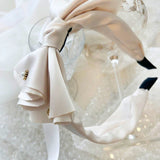 Elegant white bow headband with a large bow and pearl embellishment for special occasions